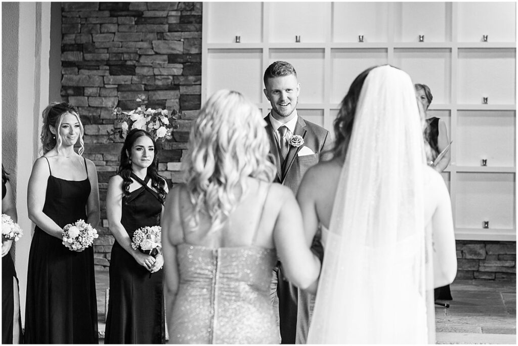 Groom looking at the bride as she walks down the aisle with her mom