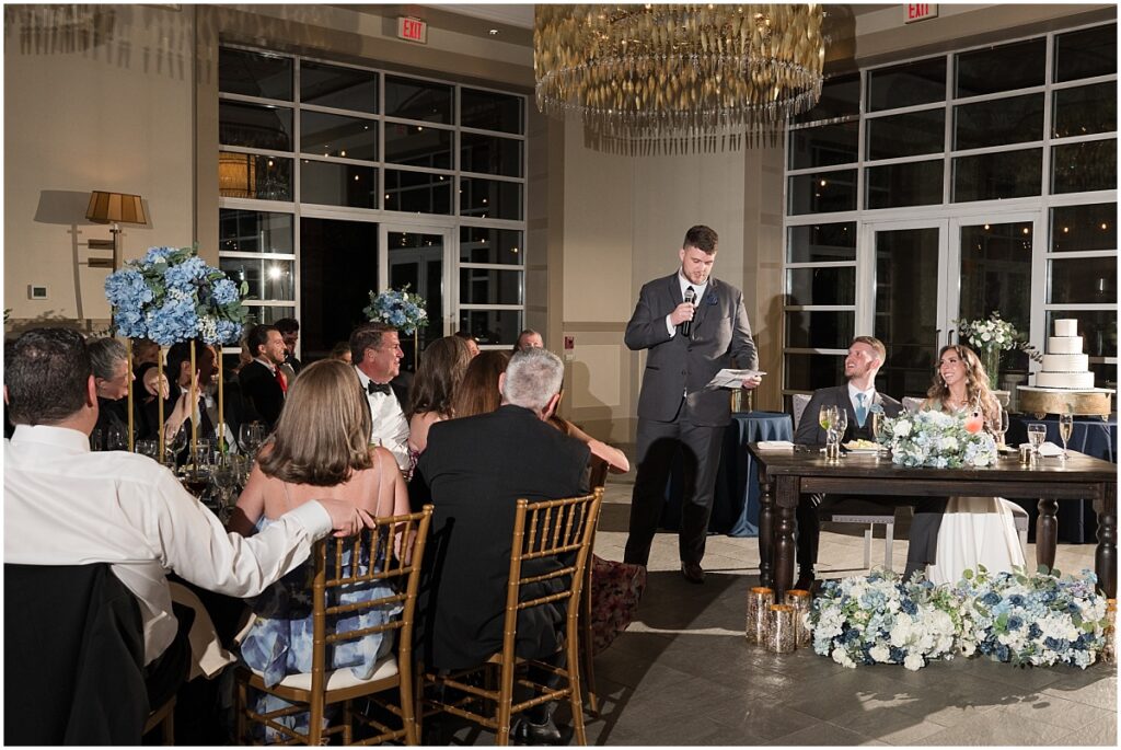 Groom giving a speech while newlyweds laugh at Stone House at Stirling Ridge 