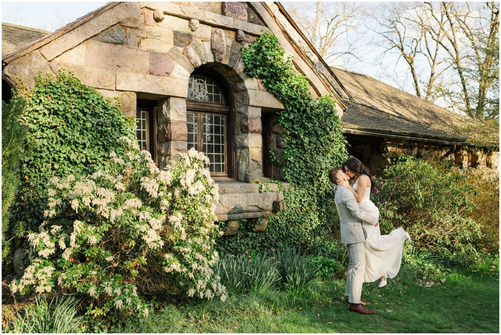 couple kissing in front of the carriage house during engagement session at the Skylands Manor