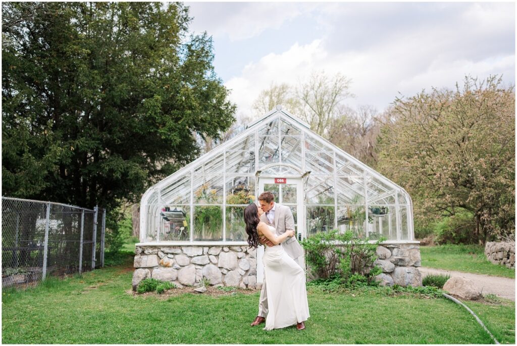 couple kissing in front of greenhouse in the Skylands Manor